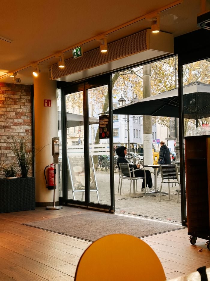 Services Charming interior view of a café in Cologne with outdoor seating and autumn ambiance.