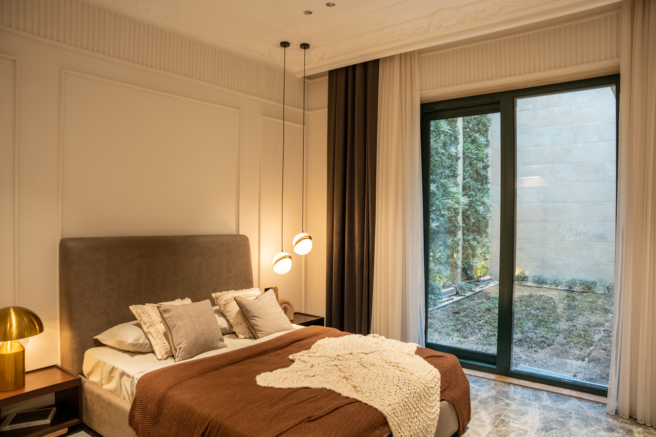Services A luxurious modern bedroom with plush decor and large sliding doors overlooking a garden.