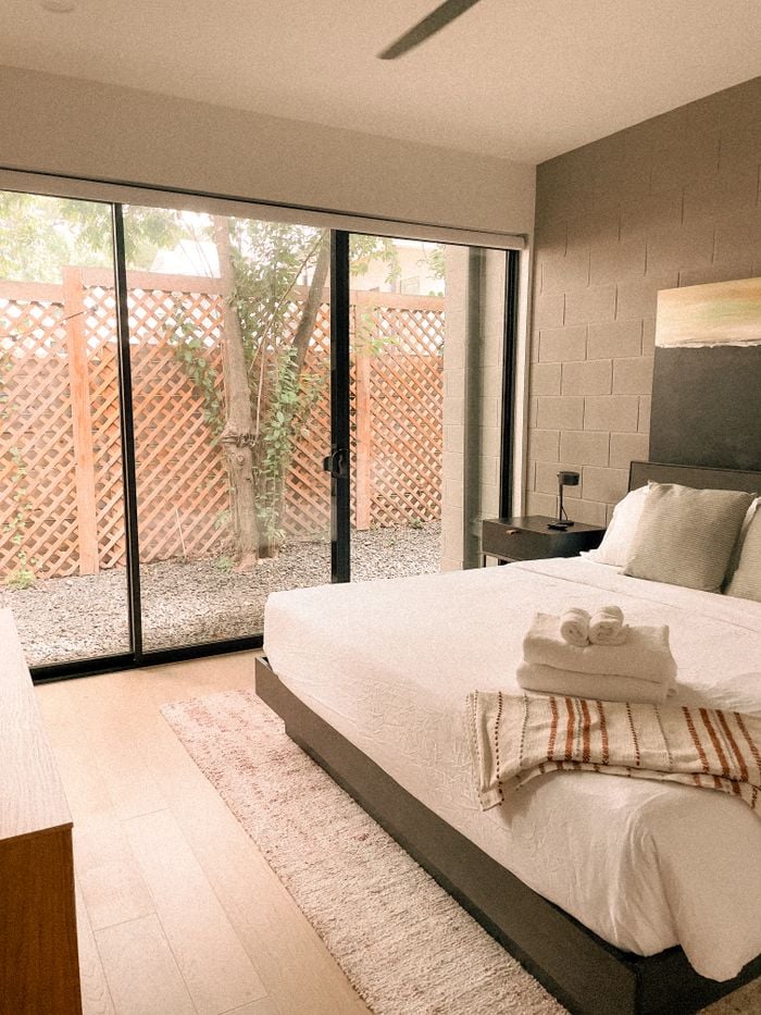 Portfolio Bright modern bedroom featuring minimalist decor and large windows with garden view.