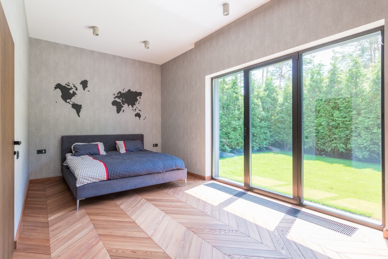 Portfolio Stylish minimalist bedroom with a bed and sliding glass doors overlooking a garden.